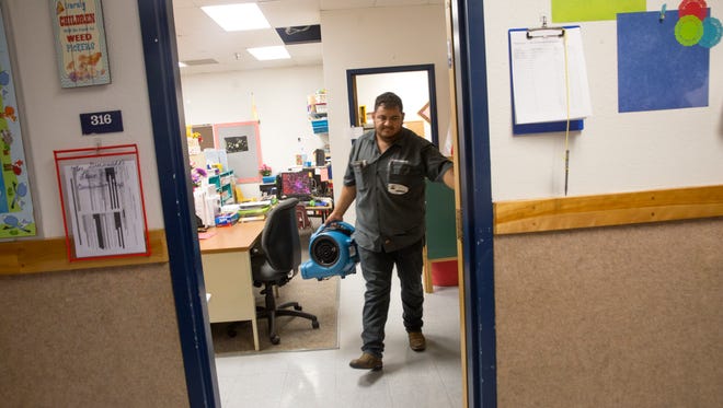 Ricardo Armendariz-Vallalba, a water technician with Mooring USA, moves equipment Thursday at Kirtland Elementary School.