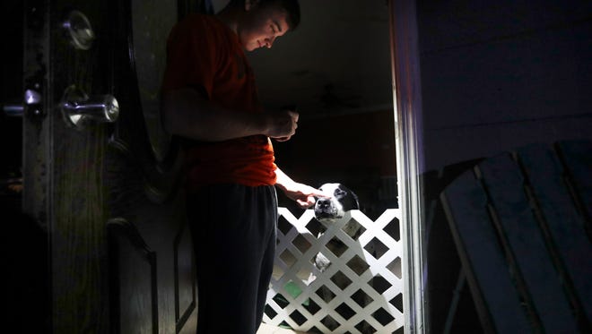 Evan Kerr carresses his dog, Dogmeat at his Lehigh Acres, Florida home on Wednesday 9/20/2017. Kerr and his mother, Melissa Bellows have been without power since Hurricane Irma plowed into the state. Kerr sleeps at his church and volunteers with recovery efforts during the day. He showers at the Wyoming Road home. Bellows, who has no generator doesn’t want to leave her home or dogs unattended. She has resorted to sleeping in front of her home. 