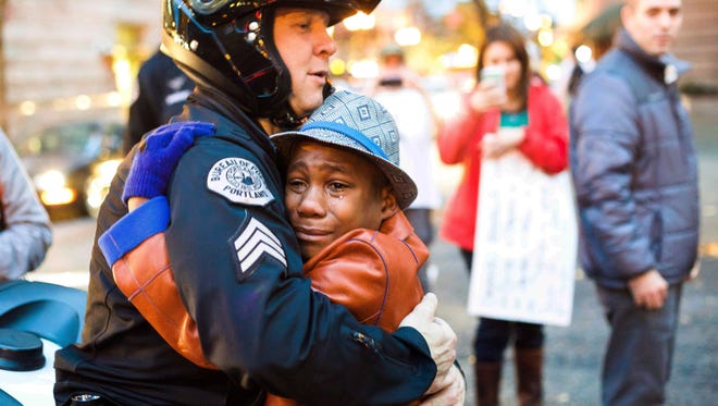 Portland police Sgt. Bret Barnum, left, and Devonte Hart, 12, hug at a rally in Portland, Ore., where people had gathered in support of the protests in Ferguson, Mo., on Tuesday, Nov. 25, 2014.