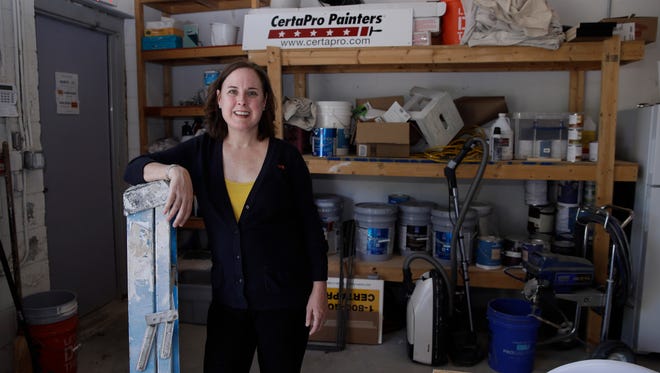 Paige NeJame, who along with her husband owns a CertaPro painting franchise, poses in a work room at her company headquarters in Rockland, Mass.
