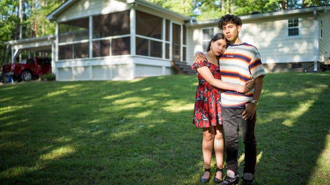 Michael Torres, 18, and his 12-year-old sister Ashley Torres in front of their home in Wake Forest, North Carolina. The family has managed to stay heatlthy, even as Michael Torres works full time with his father.