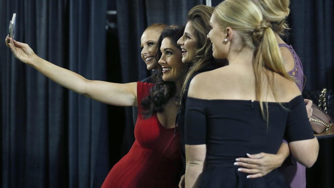Diane Hardgrove of Victor holds the phone for a selfie with other models as they get ready backstage during the Fashion Week finale show at the downtown Inner Loop.
