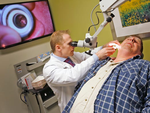 Dr. Rick Nelson, left, looks at Mark Hoffman's ear