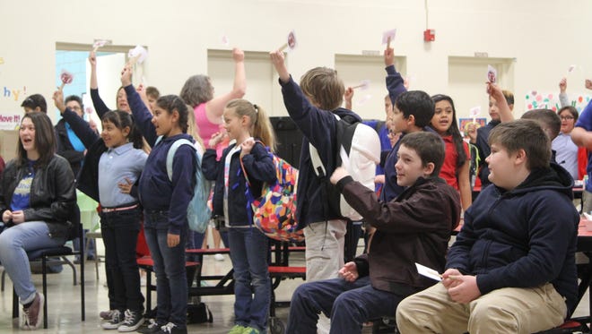 Jefferson Montessori students chant their school name and wave small signs with the school's new mascot.