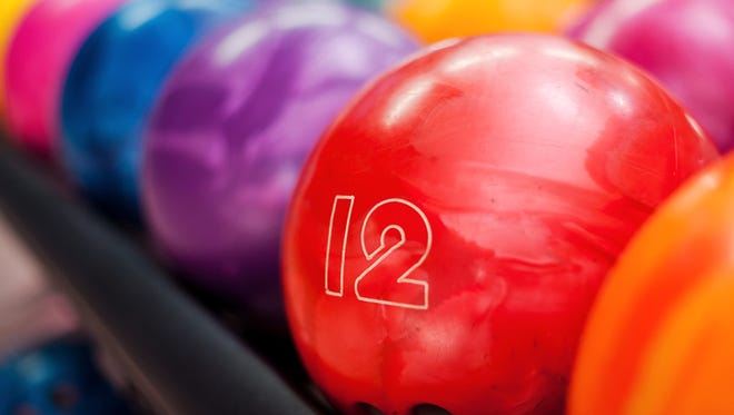 Close-up of bright red bowling ball lying in the rows of other colorful balls