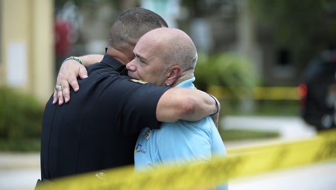 Terry DeCarlo, executive director of the LGBT Center of Central Florida, right, is comforted by an Orlando Police officer after a shooting involving multiple fatalities at a nightclub in Orlando, Fla., Sunday, June 12, 2016. (AP Photo/Phelan M. Ebenhack)