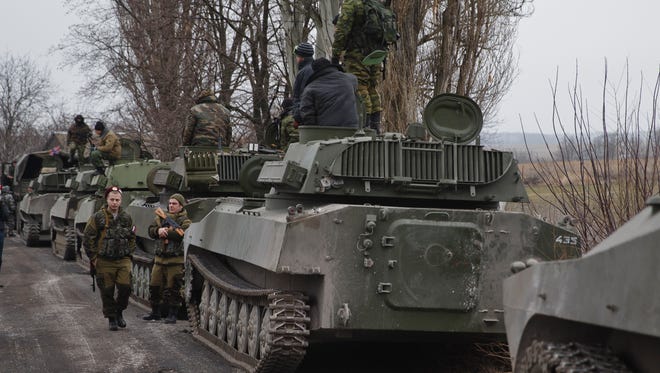 Russia-backed separatist fighters stand next to self propelled 152 mm artillery pieces, part of a unit moved away from the front lines, in Yelenovka, near Donetsk, Ukraine, on Feb. 26, 2015.