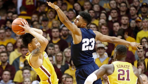 Minnesota's Amir Coffey, left, keeps the ball away from Penn State's Josh Reaves, center, during the first half of an NCAA college basketball game Saturday, Feb. 25,  in Minneapolis.