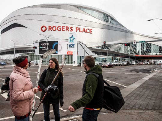 FILE - In this March 12, 2020, file photo, people talk outside Rogers Place, the home ice of the NHL hockey club Edmonton Oilers, in Edmonton, Alberta. Rogers Place is one of the possible locations the NHL has zeroed in on to host playoff games if it can return amid the coronavirus pandemic. The league will ultimately decide on two or three locations for games, with government regulations, testing and COVID-19 frequency among the factors for the decision that should be coming within the next three to four weeks.(Jason Franson/The Canadian Press via AP, File)