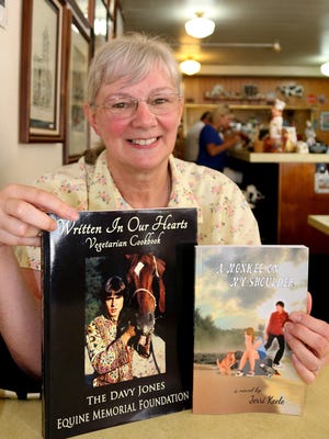 Salem author Jerri Keele holds a cookbook she helped edit with new pictures of The Monkees vocalist Davy Jones, along with a novel she’s written that features the ghost of Jones.