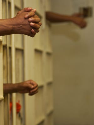 Prisoners put their hands through the bars of their cells at the Rapides Parish Jail in this Town Talk file photo. The jail continues to see overcrowding and was found in violation of the State Fire Marshal's occupancy code Friday.