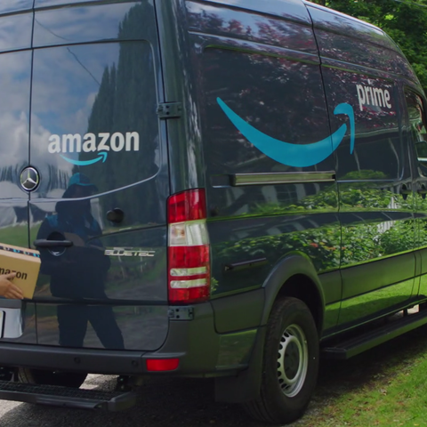 An Amazon delivery worker carries a package next t