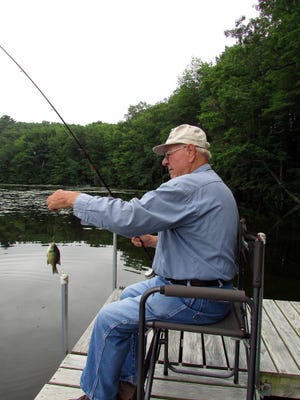 Bob Manzke pulls in a little fish from his fishing spot on the dock. 
