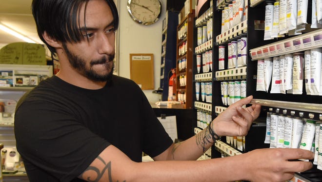 Greg Mojica, 30, assistant manager at Catskill Art & Office Supply in the Town of Poughkeepsie, reorganizes some oil paint at the front of the store.