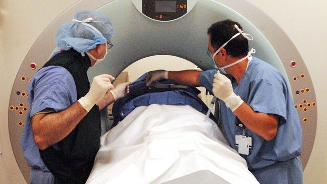 UC Health medical technicians prepare a patient for a CT scan.