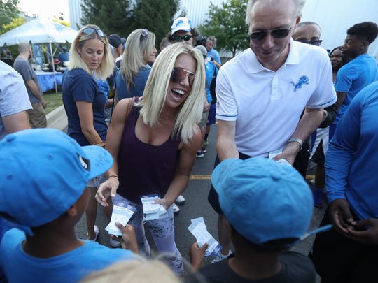 Kelly Stafford and Lions President Rod Wood distribute tickets for a pre-season game in 2016.