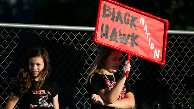 (From left to right) Williams Field fans Kailey Saenz, 15, and Alexis Lindeman, 17, pass out Black Hawk gear at the opening football game at Williams Field High School in Gilbert on Aug. 22, 2014.
