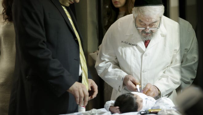Abraham Romi Cohn, right, examines Yosef Sananas before performing his bris, or ritual circumcision, in New York on Feb. 15, 2015.