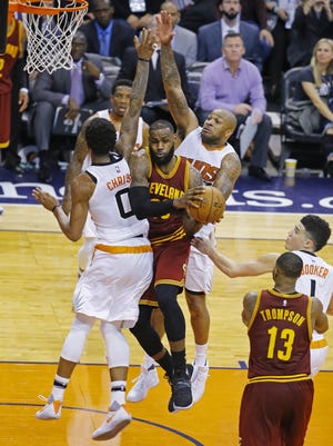 Cleveland Cavaliers forward LeBron James (23) collides with Phoenix Suns forward Marquese Chriss (0) and forward P.J. Tucker (17) during the second half of their NBA game Sunday, Jan. 8, 2017 in Phoenix, Arizona.
