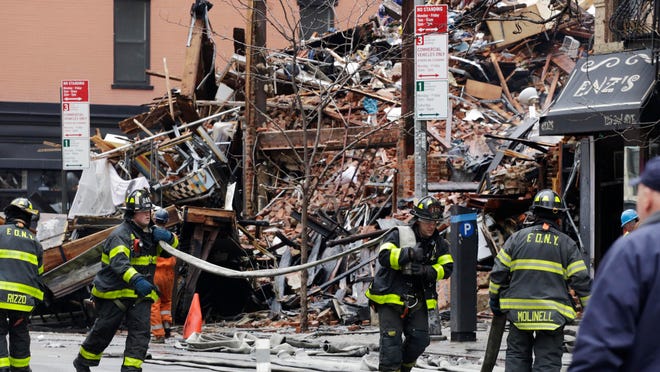 Firefighters roll up fire hoses at the site of an explosion and fire in the East Village neighborhood of New York on Friday. Authorities say two people are unaccounted for following an apparent gas explosion that leveled three buildings. Preliminary evidence suggested a gas explosion amid plumbing and gas work inside the building was to blame.