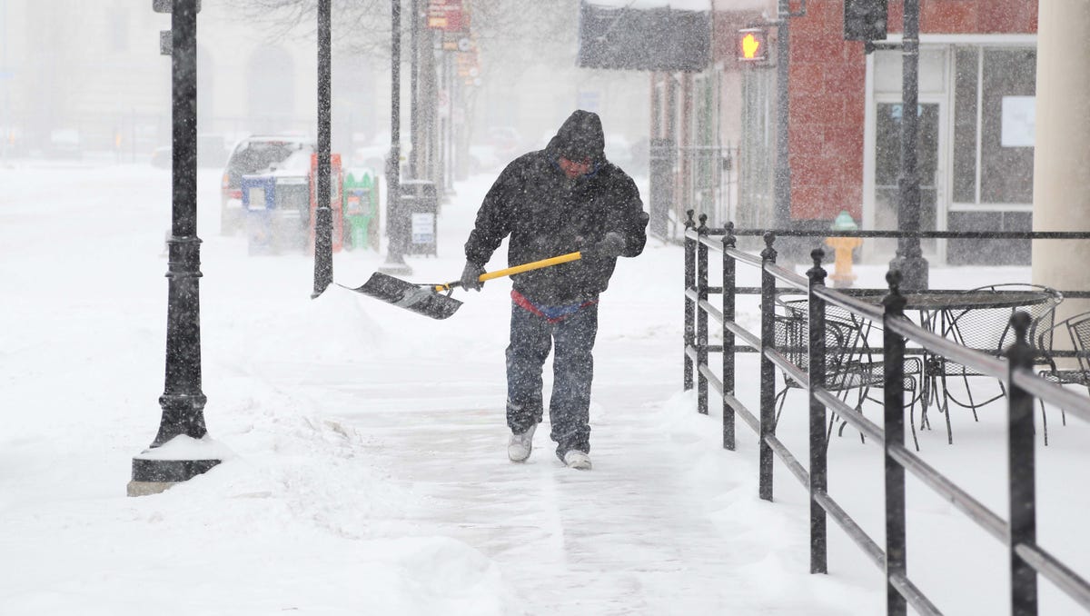 Bernardo Robles, an employee of Pints Pub N Patio shovels snow off the sidewalk outside of the business in downtown Des Moines, Iowa.