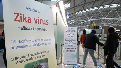 Passengers walk by a signboard about Zika virus at the passenger terminal of Incheon International Airport in Incheon, South Korea, Tuesday, March 22, 2016. South Korea on Tuesday reported the country's first case of the Zika virus, a mosquito-borne disease that has been linked to birth defects and other health issues. (Ha Sa-hun/Yonhap via AP) KOREA OUT