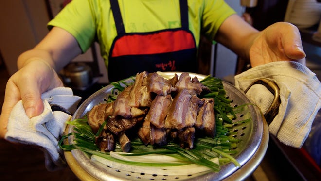 In this photo taken on Tuesday, Aug. 12, 2014, an employee of Daegyo, the dog meat restaurant, shows a dog meat before serve to customers at a restaurant in Seoul, South Korea.