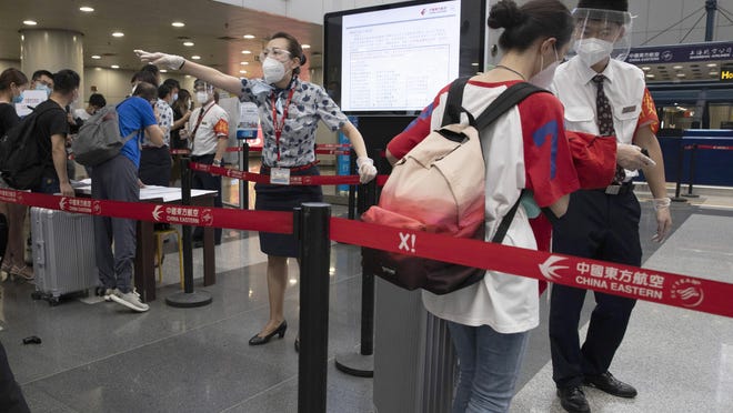 Airline staffers redirect a traveller at a checkpoint for passengers from high risk areas to present their COVID-19 test results before checking in for their flight at the Beijing Capital Airport terminal 2 in Beijing on Wednesday, June 17, 2020. The Chinese capital on Wednesday canceled more than 60% of commercial flights and raised the alert level amid a new coronavirus outbreak, state-run media reported.
