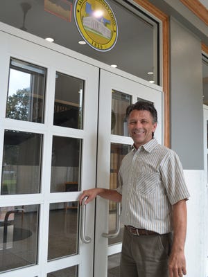 Sandusky County Commissioner Scott Miller stands below the new county seal he created. The seal is displayed over each doorway on the exterior of the renovated county courthouse.