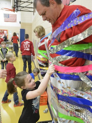 First-grader Isabel Smith duct tapes Jackson Elementary School Principal Steve Kleinfeldt to the wall during a fundraiser on Monday evening.