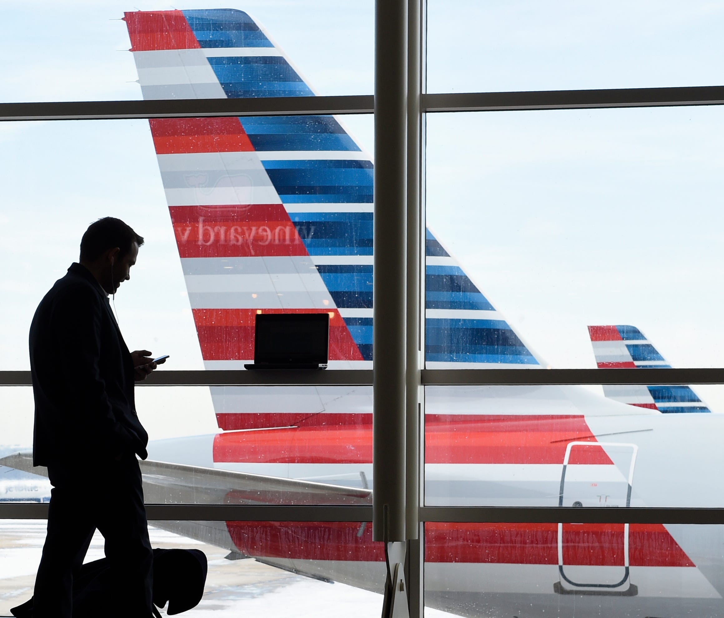 A passenger talks Jan. 25, 2016, on the phone as American Airlines jets sit parked at their gates at Washington's Ronald Reagan National Airport.