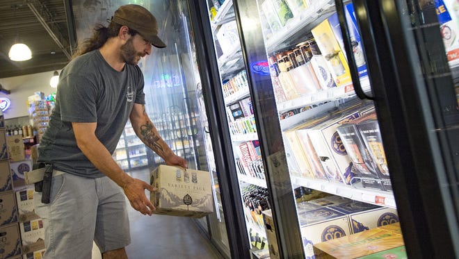 Dom Gambone selects a 12-pack of beer from Odell Brewing Company at Bullfrog Wine and Spirits on N. College Avenue on Thursday, July 27, 2017.