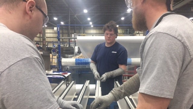 Employees in the Linetec factory work to install seals on one of the products.