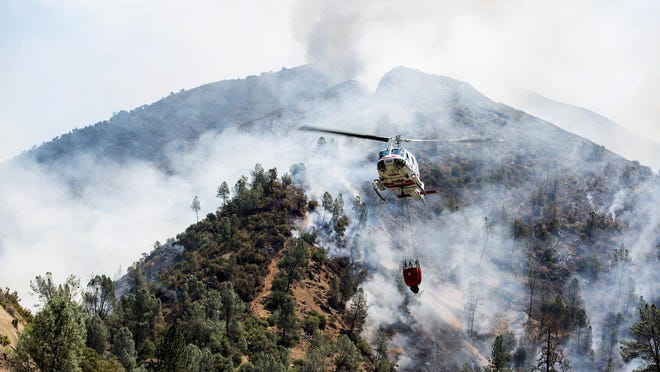 A helicopter gathers water from the Merced River to fight the Ferguson Fire along steep terrain behind the Redbud Lodge near El Portal along Highway 140 in Mariposa County, Calif., on Saturday, July 14, 2018.