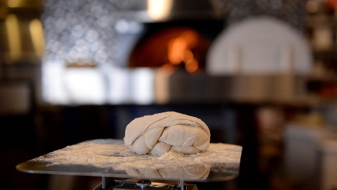 A ball of dough sits on a scale at The Cosmos. The ball of dough will eventually be made into pizza dough and cooked in the wood fired oven behind it. Diner's Drive-ins and Dives website describes The Cosmos, a Potent Potables Group venture that opened in 2015, as "an out-of-this-world pizza joint where the pie comes with a surprise."