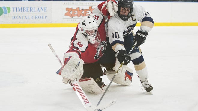 Essex’s Nicholas McGovern (10) collides with CVU goalie Ty Parker (30) while battling for the puck during the boys hockey game between the Champlain Valley Union Redhawks and the Essex Hornets at the Essex Skating Facility on Saturday.