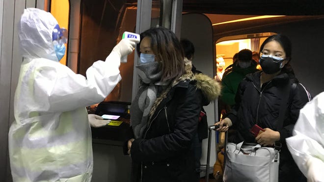 Health Officials in hazmat suits check body temperatures of passengers arriving from the city of Wuhan Wednesday, Jan. 22, 2020, at the airport in Beijing, China. Nearly two decades after the disastrously-handled SARS epidemic, Chinaâs more-open response to a new virus signals its growing confidence and a greater awareness of the pitfalls of censorship, even while the government is as authoritarian as ever. (AP Photo Emily Wang)