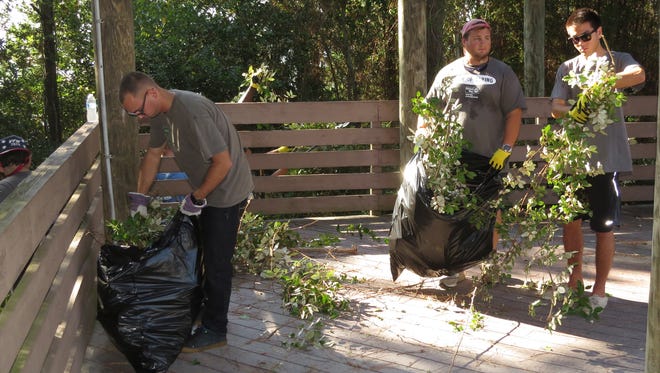 Volunteers work to cleanup trash and overgrowth in and around the Bay Bluffs Park off of Scenic Highway Friday morning as part of the United Way Day of Caring effort througout Escambia County.