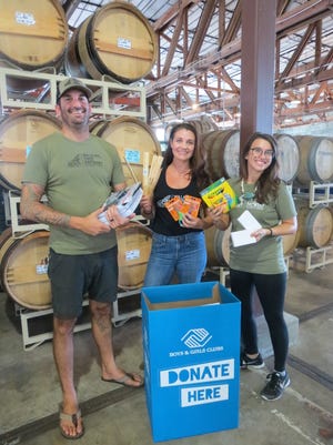 Daniel Rey, Amanda Saunders and Tess Browning of Walking Tree Brewery make the first donation to the Back 2 School Supply Drive.