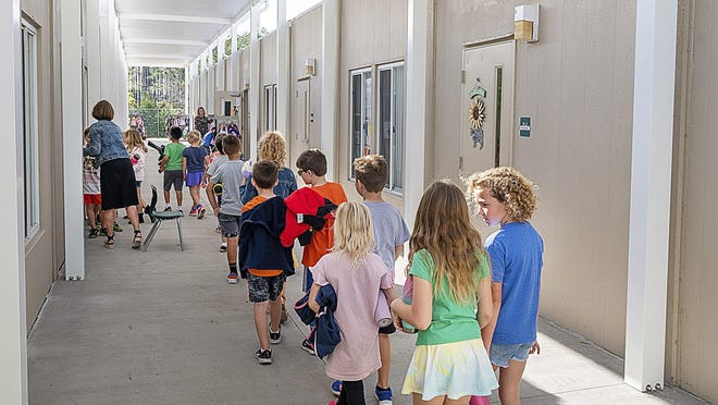 Palm Valley Academy students walk to their classroom in a row of relocatable buildings behind the school in March.