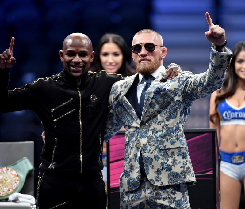 Floyd Mayweather Jr. and Conor McGregor pose for pictures during their post-fight press conference.