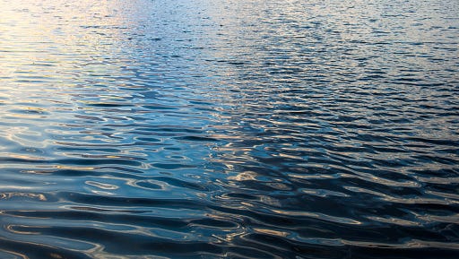 Water surface with ripples and sunrays reflections