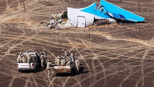 In this photo made available Monday, Nov. 2, 2015, and provided by Russian Emergency Situations Ministry, Egyptian Military on cars approach a plane's tail at the wreckage of a passenger jet bound for St. Petersburg in Russia that crashed in Hassana, Egypt, on Sunday, Nov. 1, 2015. The Russian cargo plane on Monday brought the first bodies of Russian victims killed in a plane crash in Egypt home to St. Petersburg, a city awash in grief for its missing residents. (Maxim Grigoriev/Russian Ministry for Emergency Situations via AP)