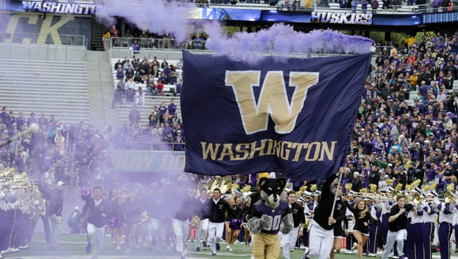 A Washington flag and the team mascot Harry the Husky leads the team on the field against  Portland State on Saturday, Sept. 17, 2016, in Seattle.