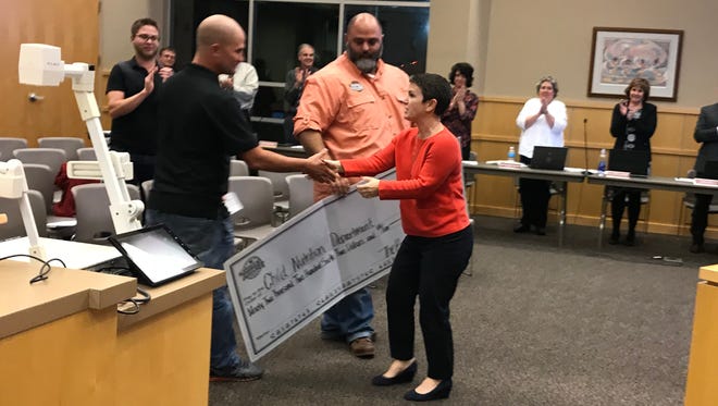 Sioux Falls School Board President Kate Parker, left, accepts a $92,000 donation from Barrel House chef Jesse Severson and owner Mark Fonder.