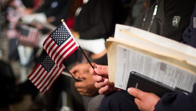 Candidates from 25 different countries hold American flags during a naturalization ceremony at the National Archives in Washington, DC, December 15, 2015, on the 224th Anniversary of the Bill of Rights.