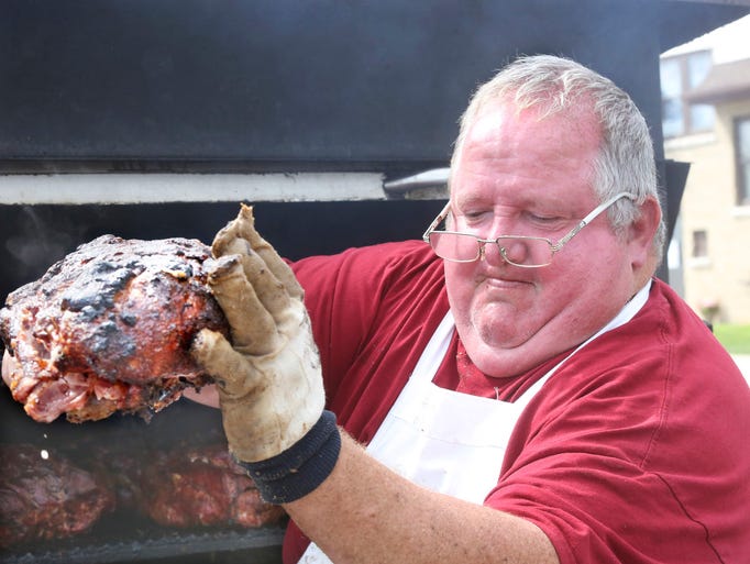 Tom Schwai pulls a pork roast from the grill to serve