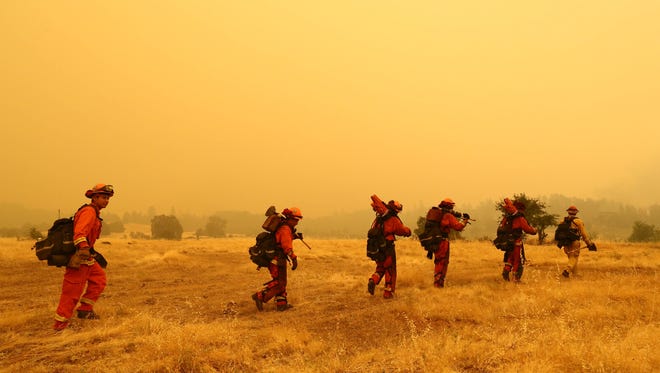 Hotshot firefighters walk on a field to build a defensive line in the Igo-Ono area. The Carr Fire spread to the southwest of Redding on Saturday morning. These images were captured along Placer Road and the Igo-Ono fire station.