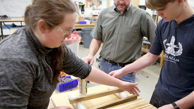 Eric Nieland, a science and technology teacher at North Kitsap High School, watches as students Katie Bagge, 15, and Nolan Patefield, 15, ready a cutting board for gluing.