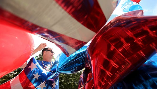 Tim Dahl untangles a group of red, white and blue balloons as he helps prepare the Calico Toy Shoppe entry for the start of Bainbridge Island's Grand Old 4th July Parade on Tuesday, July 4, 2017.